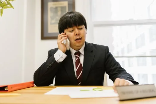 Adult child and elderly parent speaking with welfare counselor at Korean community service center desk, documents and simple phone visible, realistic photo