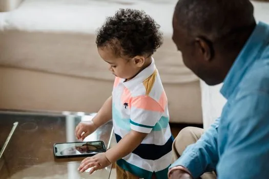 Adult child calling local clinic while checking vaccination helper website on smartphone for senior parent