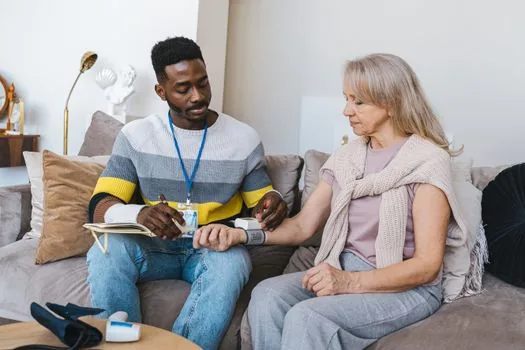 Adult child calling public health center while checking elderly parent's blood pressure notebook and diabetes prescription list at home