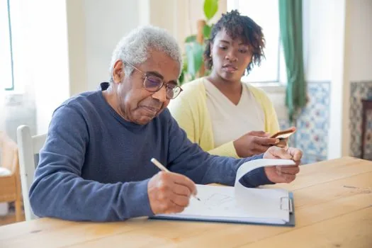 Adult child organizing long term care certificate, personal care plan and welfare equipment benefit checklist on a home table