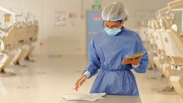 adult child speaking with public health nurse while organizing senior parent's documents in a bright clinic office, respectful realistic editorial photo