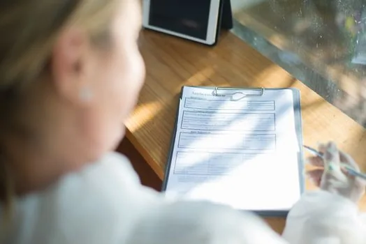 Family caregiver organizing landlord consent form, welfare certificate and home repair application documents on table