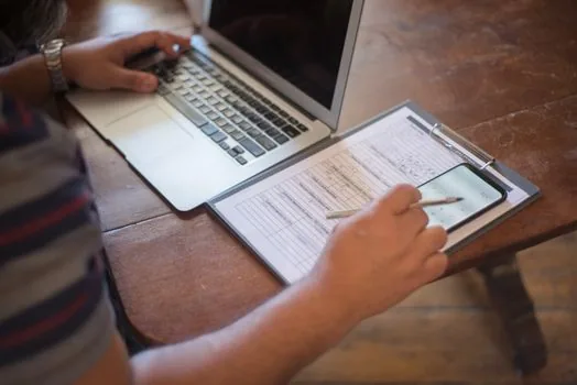Korean adult child checking land registry, farmland ledger and pension calculator beside parents, rural home desk, realistic document review photo