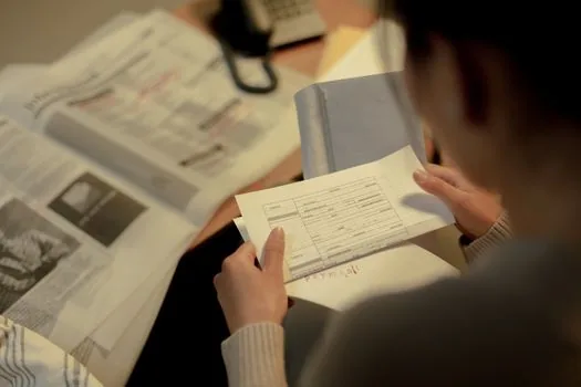 Korean adult child checking parent medical certificate income documents and welfare application checklist on kitchen table, realistic bright home care paperwork | 신청 전 진단서·소득 확인 서류 정리