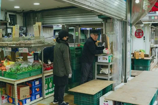 Korean community center welfare desk with application form, ID card, and grocery voucher leaflet, bright realistic editorial photo