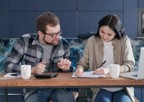 Korean family checking national health insurance premium bill income certificate and calendar on a wooden table | 가족이 건강보험료 고지서와 소득 증빙을 함께 확인하는 장면