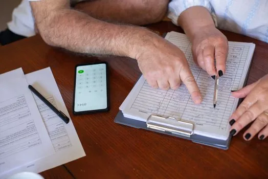 Senior couple and adult daughter calling national pension office with documents and calculator on dining table, realistic daylight photo