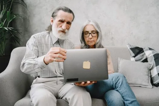 senior parent and adult child checking pension payment certificate on laptop with bankbook and reading glasses | 국민연금 지급내역 증명서 발급 화면을 가족이 함께 확인하는 장면