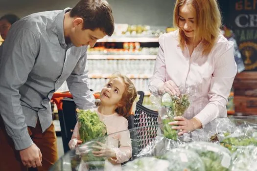 senior parent and adult child choosing fresh vegetables and eggs at a small Korean grocery store, voucher card visible, realistic editorial photo