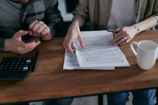 senior spouse and adult child speaking with national pension office counselor, documents and calculator on desk, realistic Korean public service editorial photo