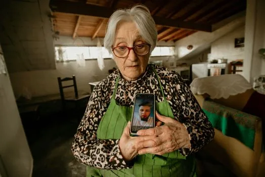 elderly parent holding smartphone while adult child writes consent checklist beside health checkup envelope, warm indoor light, realistic editorial photo