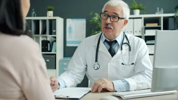 hospital billing counselor explaining caregiving copayment estimate to Korean adult child with calculator and patient chart, no text, realistic editorial photo | 병원 상담 직원이 보호자에게 간병비 본인부담 예상액을 설명하는 장면