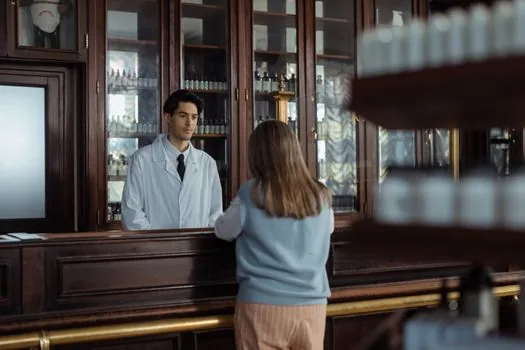hospital pharmacy counter with caregiver receiving medicine bag, pharmacist explaining dosage note, no personal data visible, realistic Korean senior healthcare photo | 약국에서 부모님 약 복용법을 다시 확인하는 장면