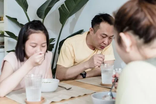 Korean adult child calling a local clinic while checking elderly parent's flu vaccination schedule and ID card on a dining table | 부모님 독감 접종 시작일과 병원 전화 확인을 준비하는 장면