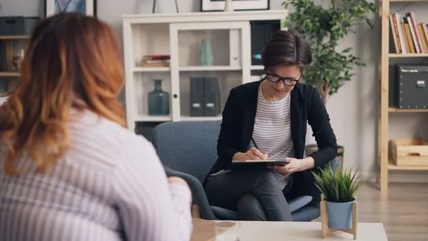 Korean adult child gently preparing mental health counseling notes with senior parent at a warm home table