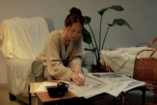 Korean adult child organizing hospital discharge papers, medication list and community care application notes beside elderly parent at home, realistic warm editorial photo