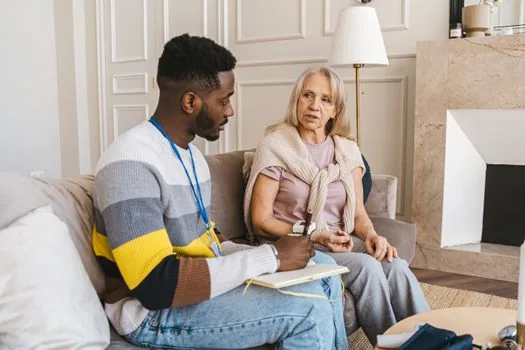 Korean life support worker visiting senior home, checking safety and meal plan with adult child nearby, realistic respectful photo | 선정 뒤 안부확인과 생활지원 계획을 상담하는 장면
