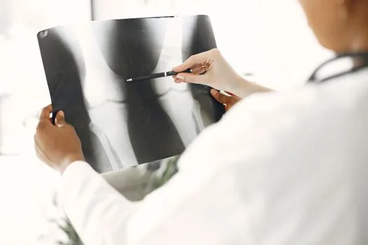 Korean orthopedic doctor explaining knee replacement schedule to elderly parent and adult child with medical cost documents on desk | 정형외과에서 부모님 무릎 수술 일정과 지원 서류를 상담하는 장면