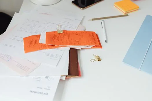 senior parent bankbook, hospital receipt, refund application memo and smartphone verification screen on desk, realistic Korean home photo | 환급금 계좌 등록 전 필요한 정보를 정리하는 장면